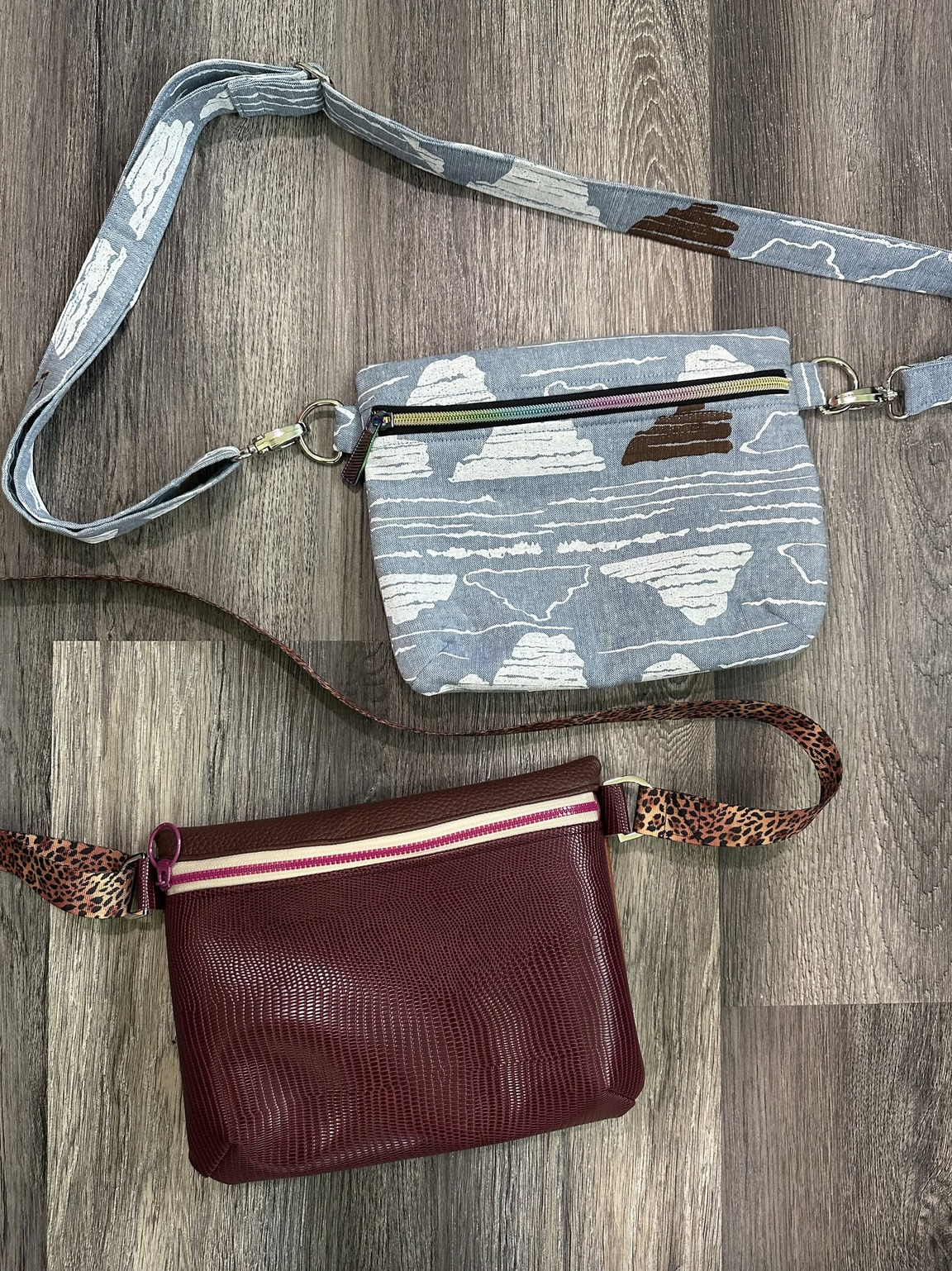Two Reine Crossbody Bags laying on wooden surface